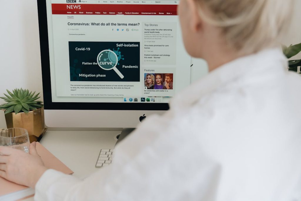 A woman in a home office reads online news about Covid-19 on a desktop computer.